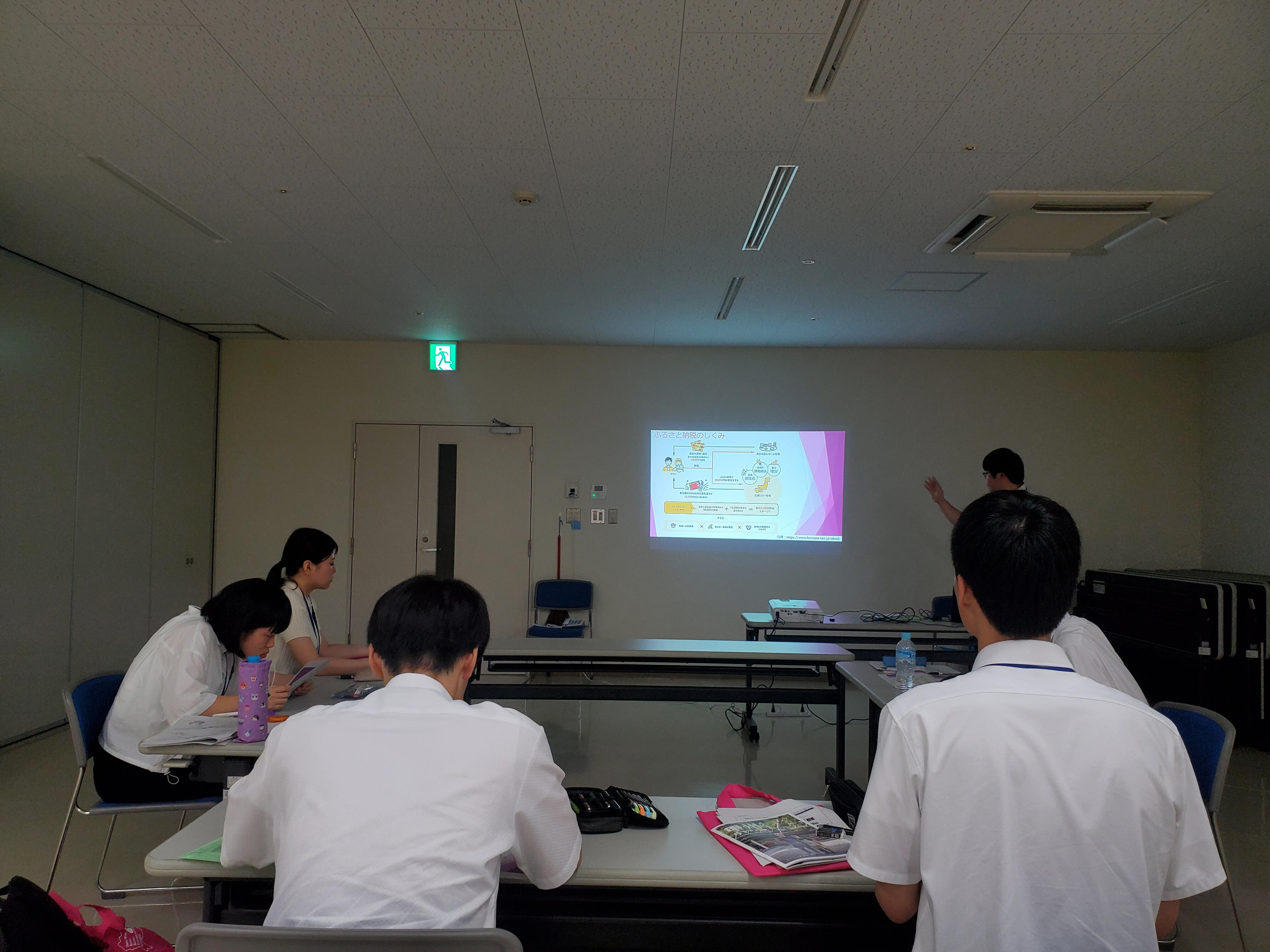市担当者からふるさと納税について説明を受ける大学生たち